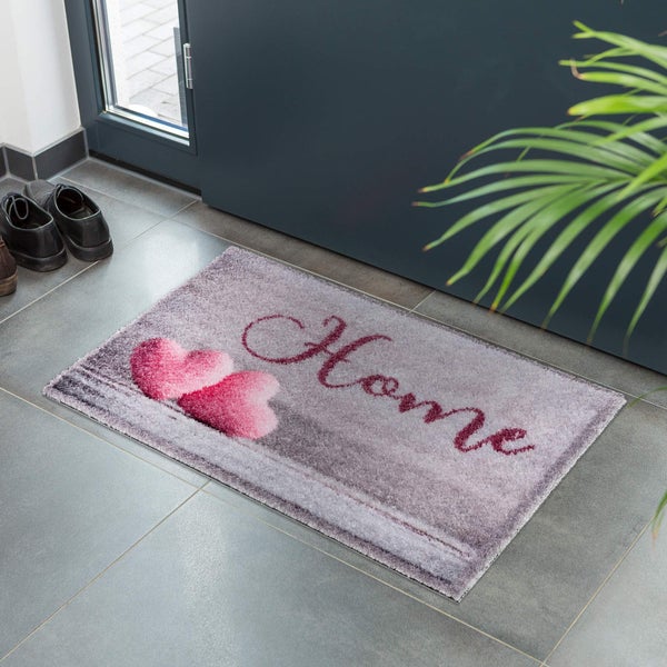 Fußmatte mit Herzen und dem Schriftzug Zuhause vor einer Tür
