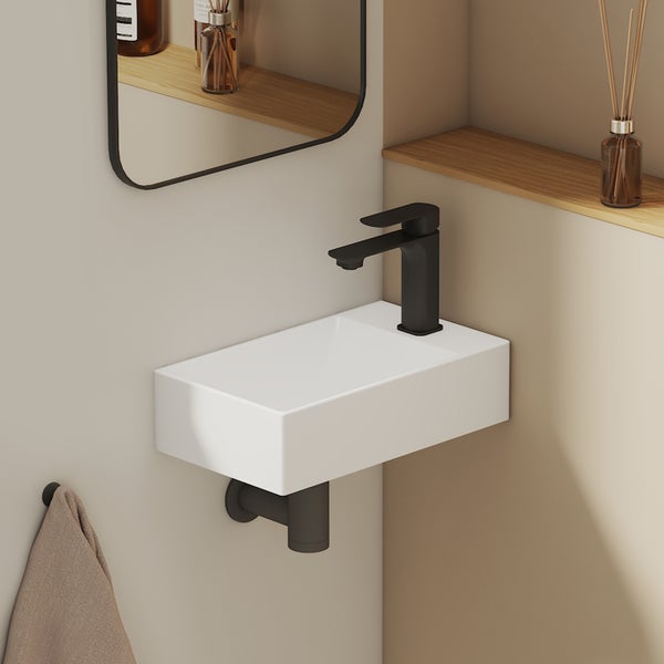 Moderne Gäste-Toilette mit einem weißen rechteckigen Wand-Handwaschbecken, schwarzer Armatur und schwarzem Siphon in minimalistischem Design.