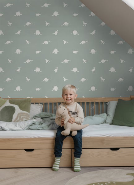 Vliestapete mit Dinosaurier-Silhouetten in einem hellen Kinderzimmer mit einem Bett aus Holz und einem Kind.