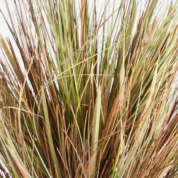 Künstliches Gras mit grünen und braunen Halmen im schwarzen Kunststofftopf.