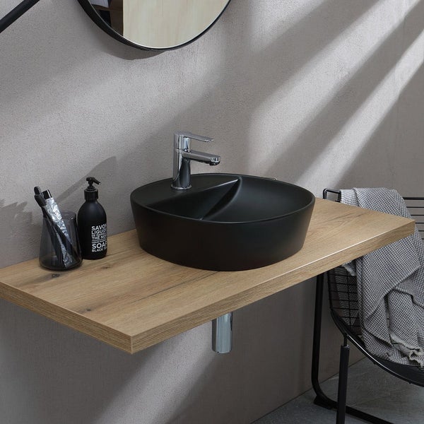 Modernes Aufsatzwaschbecken aus schwarzer, matter Keramik auf einer Holz-Waschtischplatte mit verchromter Armatur im minimalistischen Badezimmer.