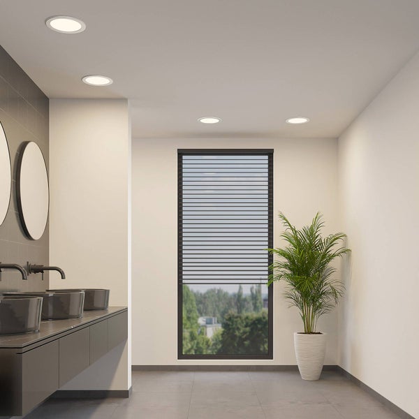 Modernes Badezimmer mit runden Einbaustrahlern an der Decke, Doppelwaschtisch, großem Fenster mit Jalousie und einer Zimmerpflanze.