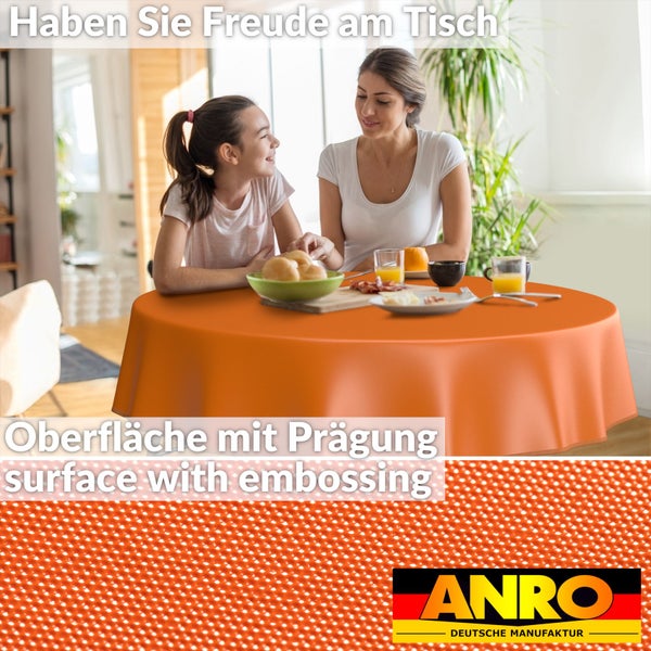 Mutter und Tochter sitzen an einem runden Tisch mit orangefarbener Tischdecke und genießen eine Mahlzeit. Detailaufnahme der Tischdeckenoberfläche mit Prägung und dem Anro Deutsche Manufaktur Logo.