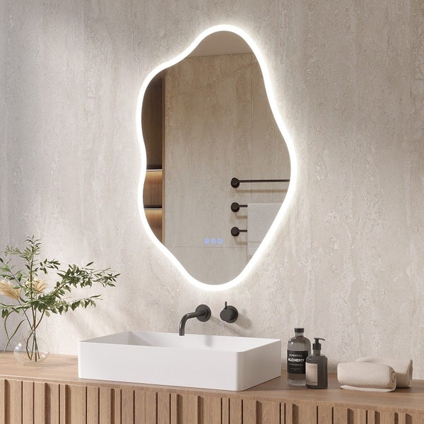 Organisch geformter Wandspiegel mit LED Beleuchtung und Touch Funktion über einem Waschtisch mit Aufsatzwaschbecken und dunkler Armatur.