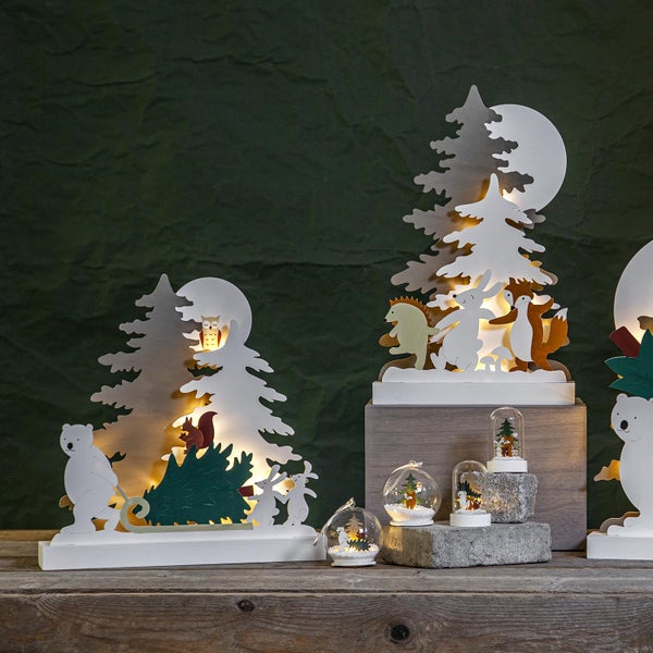 Dekorative Weihnachtsszene mit Holztieren, Bäumen und beleuchteten Schneekugeln