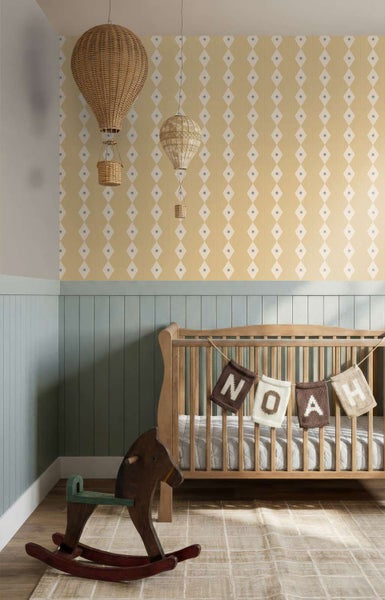 Ein Kinderzimmer mit gemusterter Tapete, hängenden Heißluftballon Dekorationen aus Rattan, einem Holzgitterbett und einem Schaukelpferd.