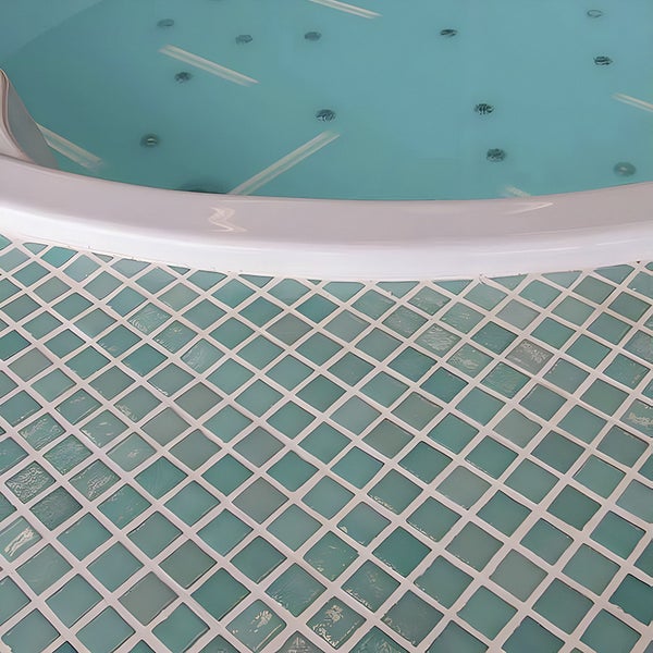 Whirlpool Wannenrand mit angrenzendem Mosaikfliesenbelag in einem Badezimmer.