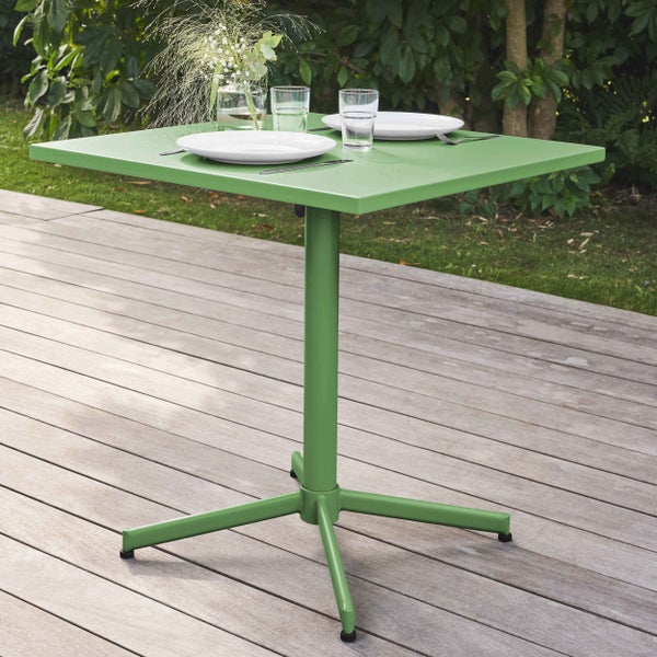 Grüner quadratischer Gartentisch aus Metall auf einer Holzterrasse, gedeckt mit Tellern und Gläsern für zwei Personen.