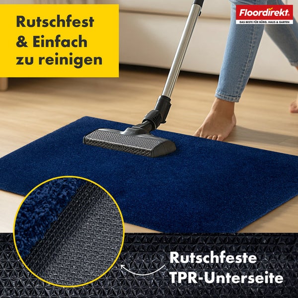 Blaue Fußmatte wird mit einem Staubsauger gereinigt. Die Rückseite der Matte ist rutschfest.