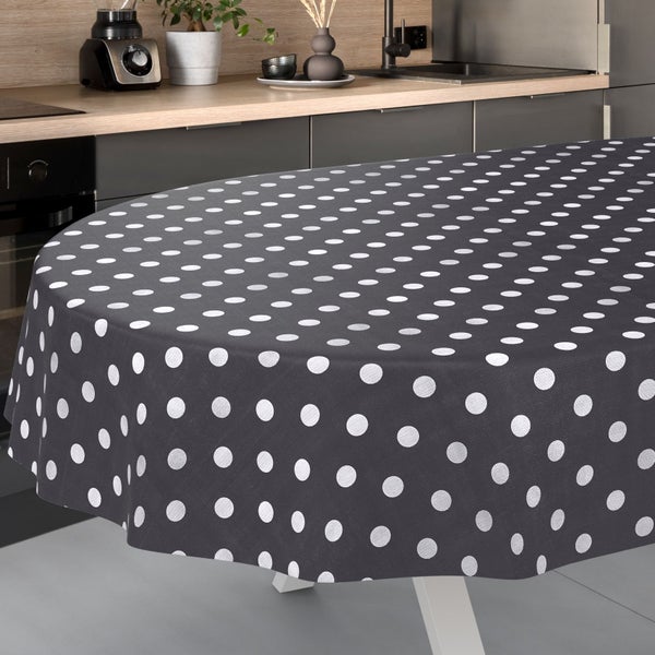 Runde Tischdecke mit Punktmuster auf einem Tisch in einer hellen, modern eingerichteten Küche mit Küchenschränken und Spüle.