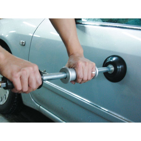 Eine Dellenreparatur mit einem Ausbeulwerkzeug an einem Auto