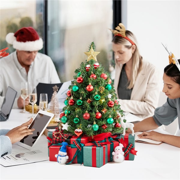 Festlich geschmückter Schreibtisch mit Weihnachtsbaum, Geschenken und Büroangestellten in weihnachtlicher Stimmung