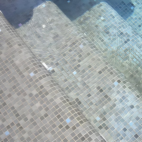 Unter Wasser liegende Treppe eines Schwimmbeckens mit Mosaikfliesenbelag.