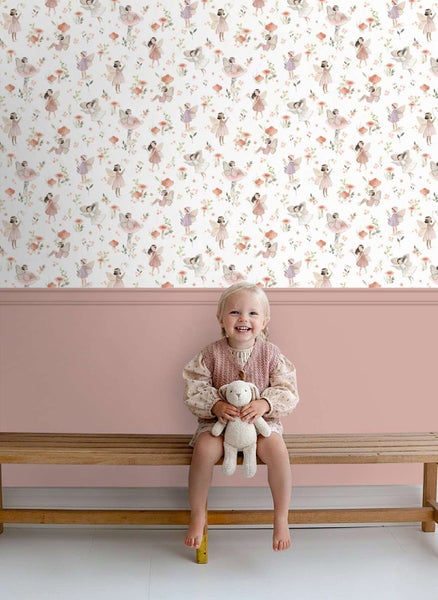 Kindertapete mit Feen-Motiv und Pilzen in einem Kinderzimmer mit einer Holzbank und einem kleinen Mädchen mit Kuscheltier.