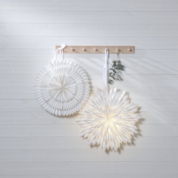 Dekorative Papiersterne hängen an einer Holzgarderobe an einer Holzwand