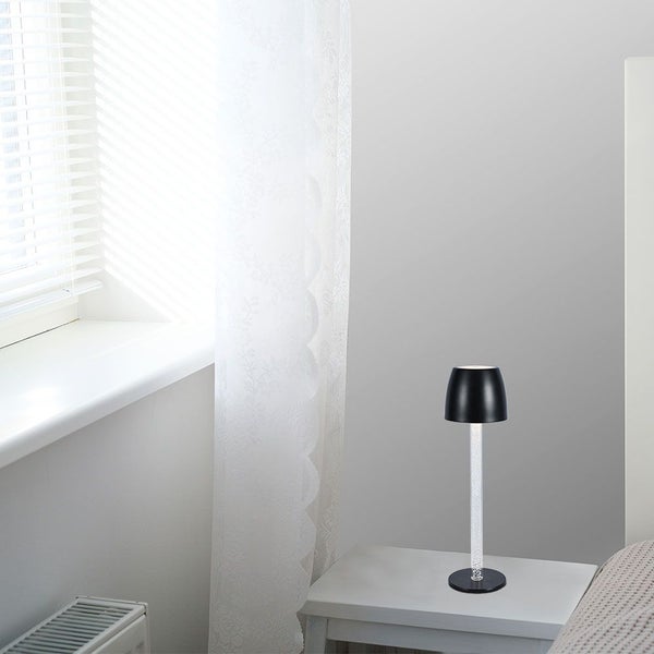 Dekorative Tischleuchte mit transparentem, mit Luftblasen gefülltem Leuchtenfuß auf einem Nachttisch