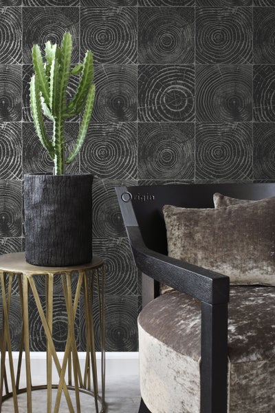 Dekoratives Interieur mit Kaktus, Beistelltisch und Sessel vor einer gemusterten Wand