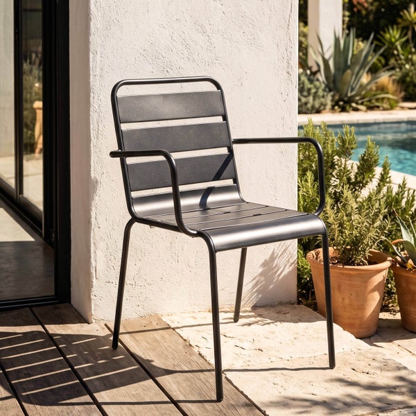 Moderner Gartenstuhl mit Armlehnen aus Metall auf einer hellen Terrasse mit Holzdeck und Steinboden neben einem Pool.