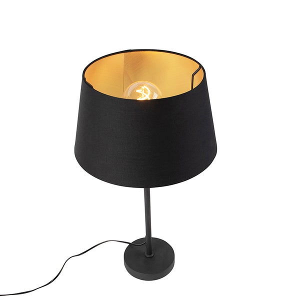 Tischleuchte mit schwarzem Stoffschirm, goldfarbener Innenseite, rundem schwarzem Standfuß und leuchtender Glühbirne.