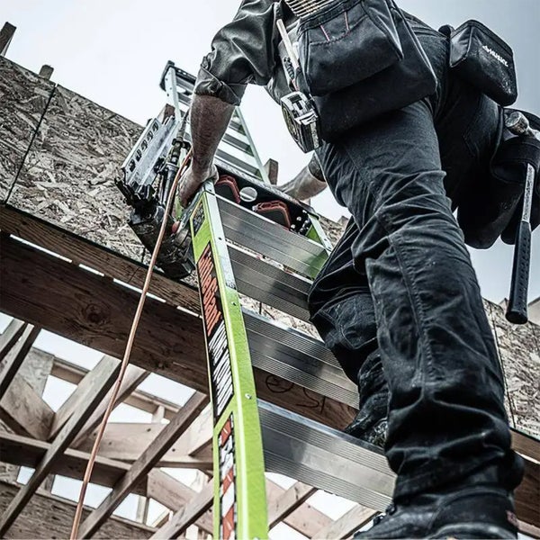 Handwerker auf einer Stehleiter bei Holzarbeiten an einer Baustelle mit Druckluftnagler