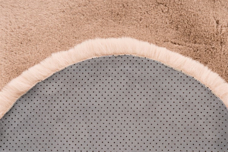 Nahaufnahme eines Hochflor-Teppichs aus Kunstfell mit weichem Flor und rutschhemmender Rückseite mit Noppen.