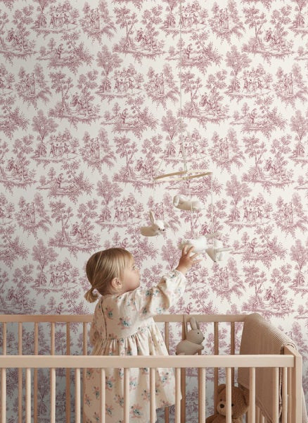 Helles Kinderzimmer mit Toile-de-Jouy-Tapete, einem Holzgitterbett und einem Kleinkind, das nach einem Mobile greift.
