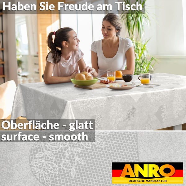 Helle Szene mit Frau und Kind an einem Tisch mit ANRO Tischdecke, feines florales Muster, glatte Oberfläche. ANRO Logo.