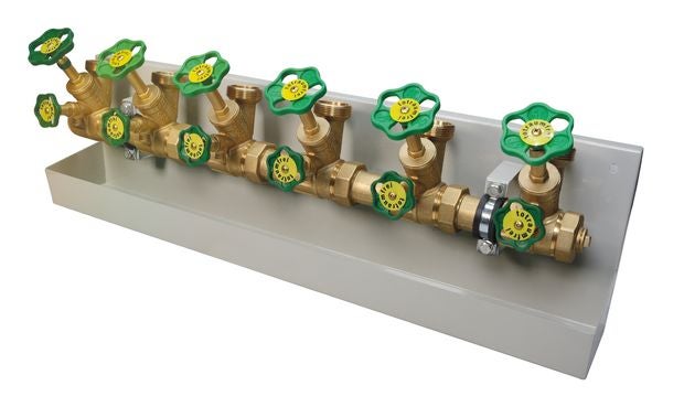 Wasserzähler-Verteiler aus Messing mit totraumfreien Ventilen und grünen Handrädern auf einer Wandhalterung.