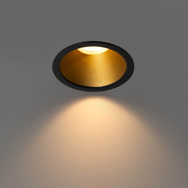 Runder LED-Einbaustrahler mit schwarzem Außenring und goldener Innenseite, der einen warmen Lichtstrahl abgibt.