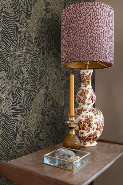 Dekoratives Zimmer mit gemusterter Tapete, Lampe, Kerze und Dekorationen auf einem Tisch