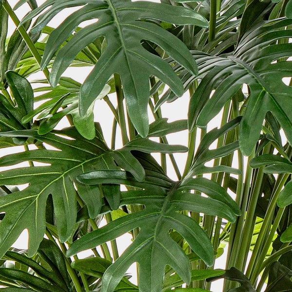 Nahaufnahme der grünen, tief gelappten Blätter einer künstlichen Philodendron-Pflanze.