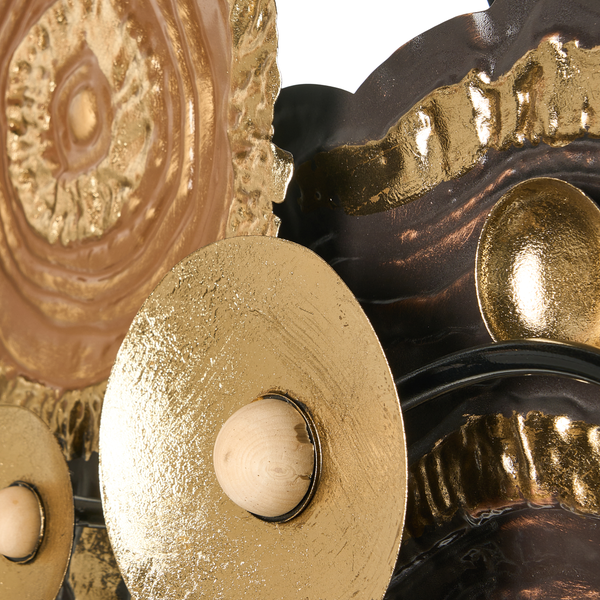 Detailansicht einer Wanddekoration aus strukturierten Metallscheiben in Gold und Braun mit Elementen aus Holz.