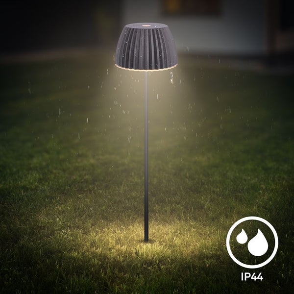 Garten-Stehleuchte mit Falten-Schirm auf Rasen bei Nacht und Regen, Schutzart IP44 gegen Spritzwasser.