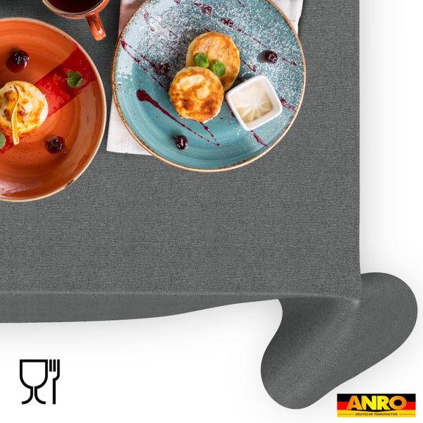 Texturierte Tischdecke aus Stoff mit Tellern und Speisen. Lebensmittelecht Symbol und ANRO Logo.