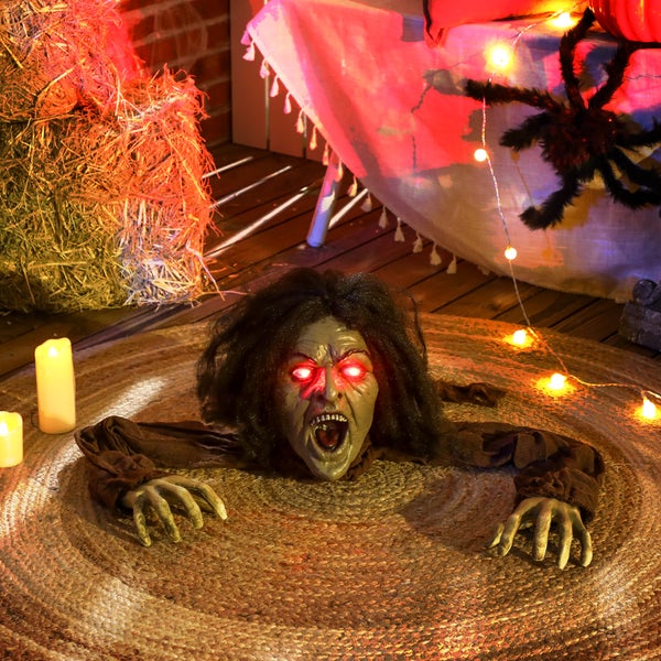 Dekorative Halloween-Szene mit einer Zombie-Figur, Heuballen und Lichtern.