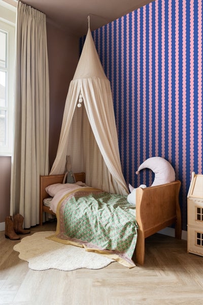 Kinderzimmer mit Himmelbett, gemusterter Tapete und Holzfußboden