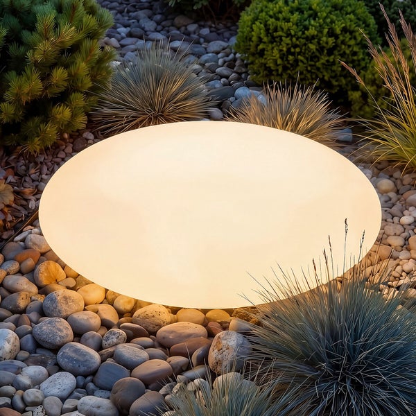 Ovale Gartenleuchte in Steinoptik, leuchtend in einer Gartenlandschaft mit Kieselsteinen und Ziergräsern.