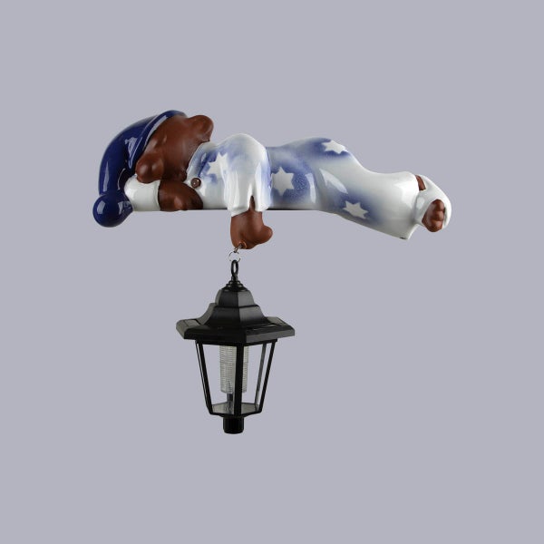 Gartenfigur schlafender Bär im Schlafanzug mit hängender Solarleuchte.