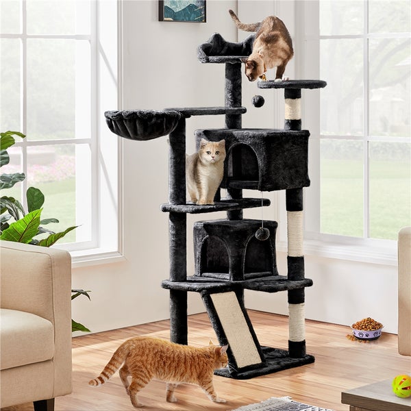 Katzenkratzbaum mit mehreren Ebenen, Häusern, Hängematte und Kratzstämmen in einem Wohnzimmer mit drei Katzen.