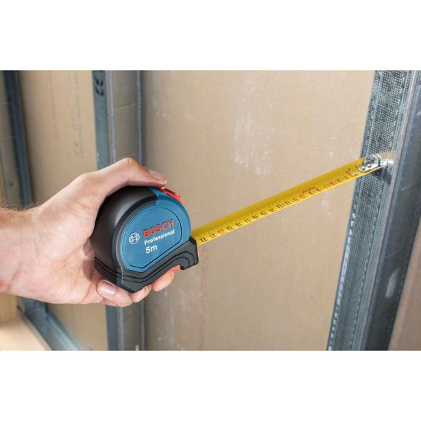 Hand hält Bosch Professional Rollbandmaß mit 5 Metern Länge an einer Wand