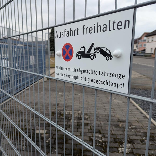 Hinweisschild Ausfahrt freihalten mit Abschlepphinweis am Metallzaun