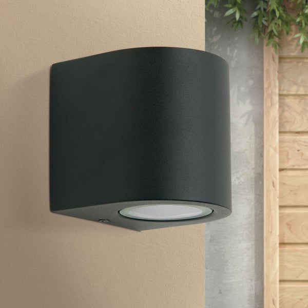 Moderne Außenwandleuchte in Schwarz mit abgerundeter Form, an einer Wand montiert.