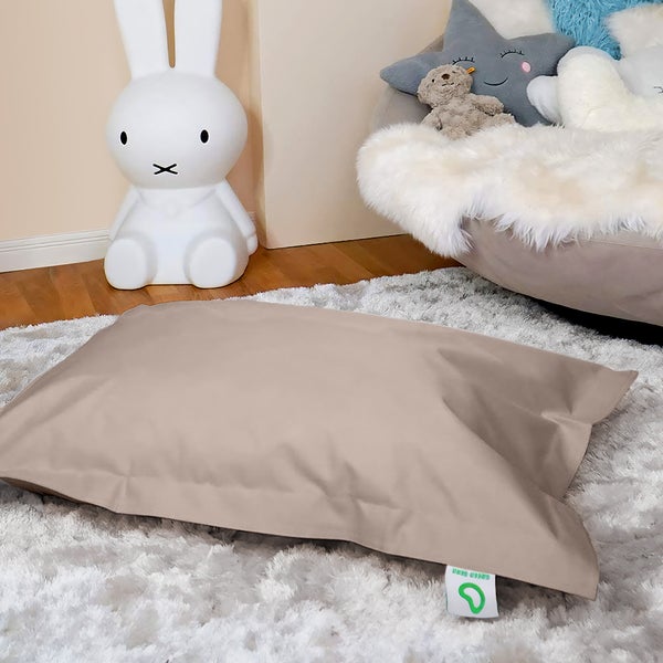 Beiger Sitzsack auf einem Teppich, zusammen mit einer Hasenlampe und einem Sessel mit Kissen