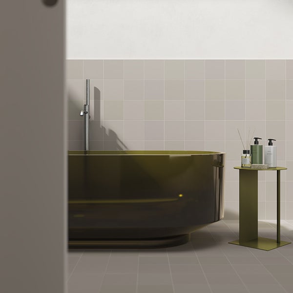 Moderne Badezimmereinrichtung mit einer ovalen Badewanne, einer freistehenden Armatur und einem Beistelltisch vor hellen quadratischen Fliesen.