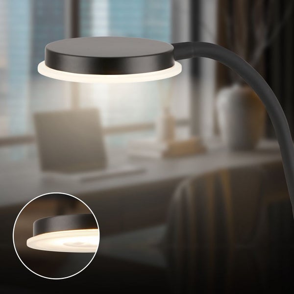 Schwarze LED Schreibtischlampe mit flexiblem Arm und rundem Leuchtkopf, Detailansicht der eingeschalteten Lichtquelle.