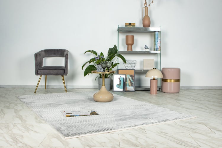 Modernes Wohnzimmer Interieur mit gepolstertem Stuhl, Beistelltisch, Regalsystem, Dekorationsobjekten und Teppich auf Boden mit Marmoroptik.