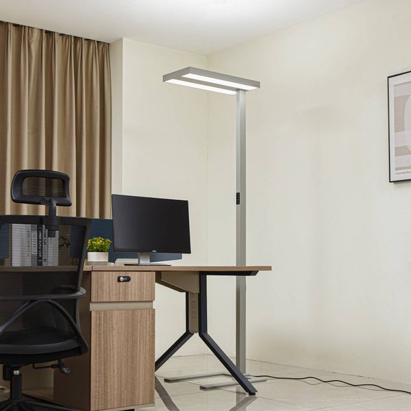 Moderne LED Stehleuchte aus Metall an einem hellen Büroarbeitsplatz mit Schreibtisch, Monitor und ergonomischem Bürostuhl.
