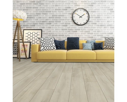 Helles Wohnzimmer mit gelbem Sofa, Kissen, Bildern, Stehlampe, Uhr und Laminatboden.