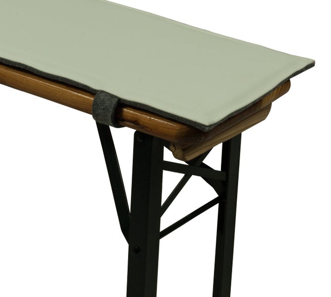 Graue Gartenbank aus Kunststoff vor weißem Zaun und Grünpflanzen