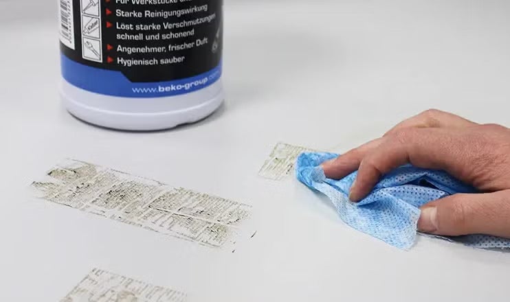 Person reinigt eine Oberfläche mit Reinigungsmittel von Beko und einem Reinigungstuch.